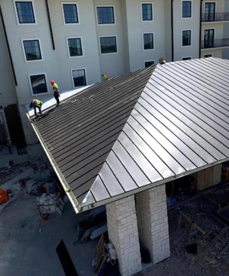 Crew installing standing seam metal roof panels on a commercial project in Buckhead